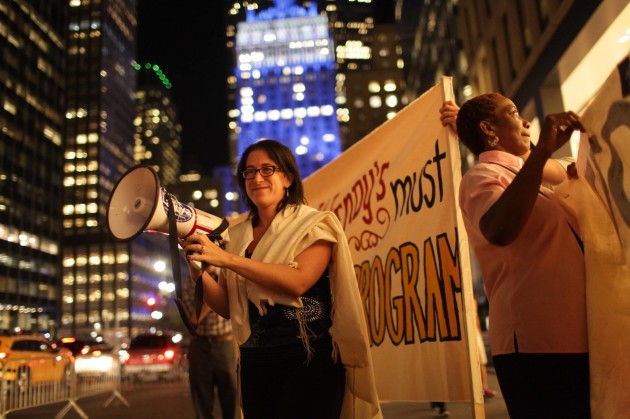 Rabbi Rachel Kahn-Troster holds a megaphone as she stands outside a protest of Wendy's. 